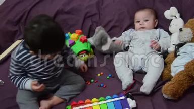 两岁和四个月大的男孩在床上玩木琴和软玩具
